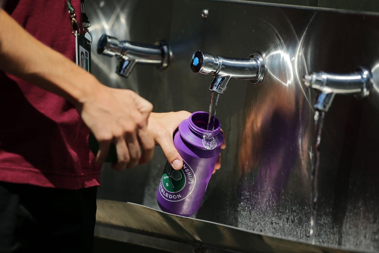 Person refilling a reusable water bottle with water.